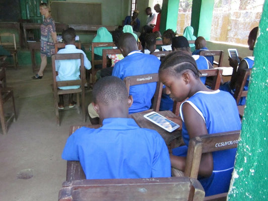 Students in blue uniforms learning on tablets.