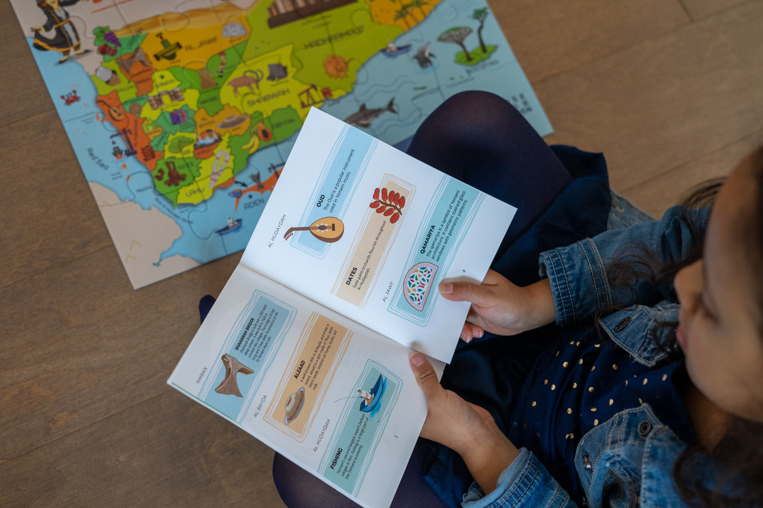 Girl sitting on floor reading the Treasures of Yemen booklet.