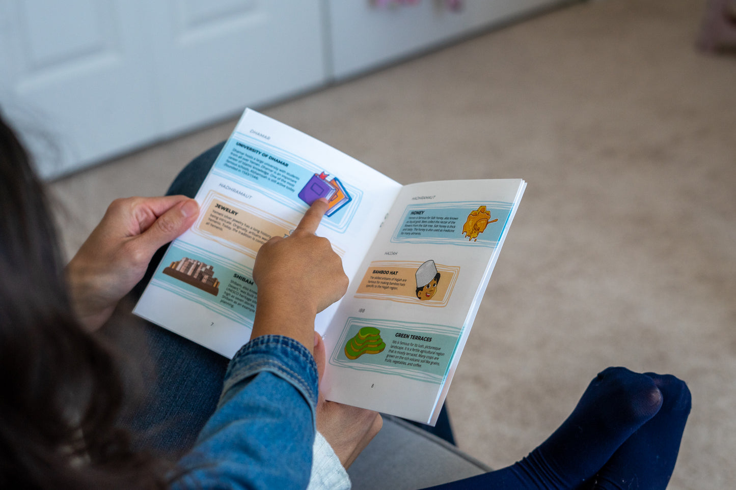 Little girl pointing to a booklet for the Treasures of Yemen.